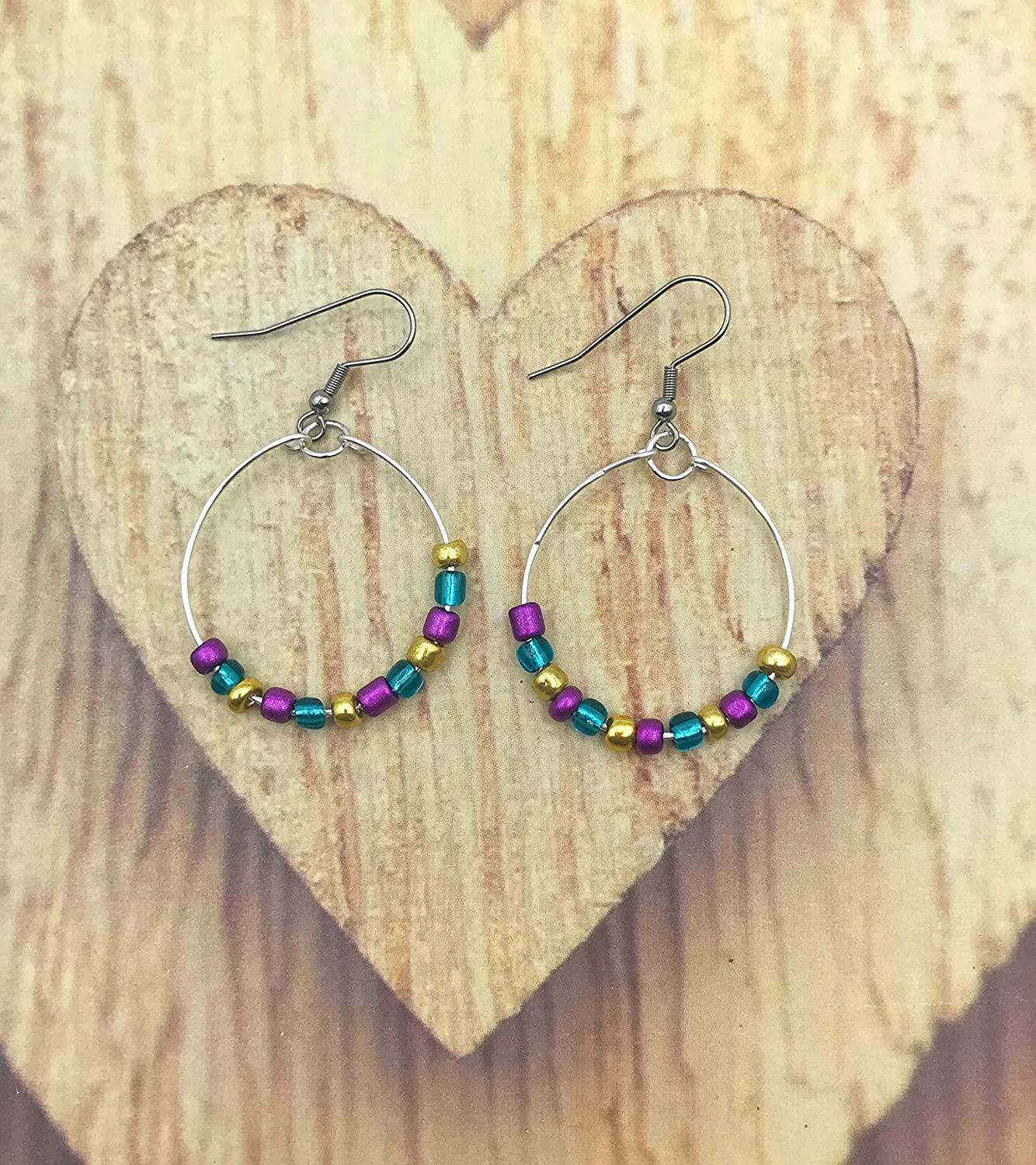 Mardi Gras Beaded Hoop Earrings displayed on a wooden heart  from Scott D Jewelry Designs